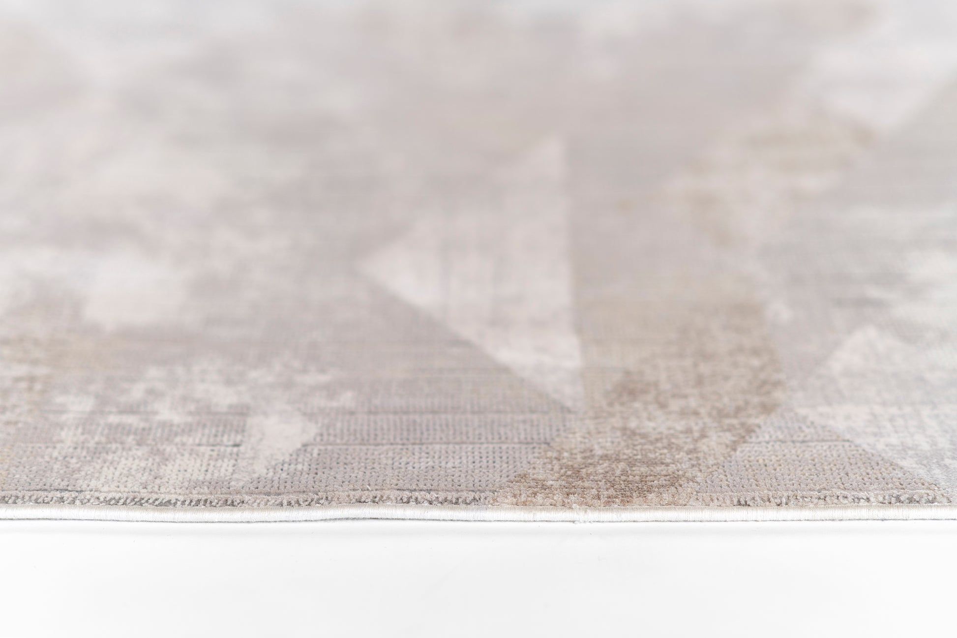 Light gray geometric rug with subtle triangle pattern and flat-weave texture, edge visible.