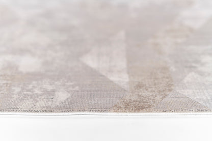 Light gray geometric rug with subtle triangle pattern and flat-weave texture, edge visible.
