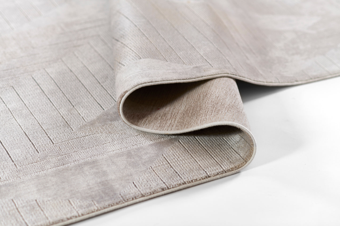 Beige-gray woven area rug with subtle linear border and folded edge, soft textured weave.