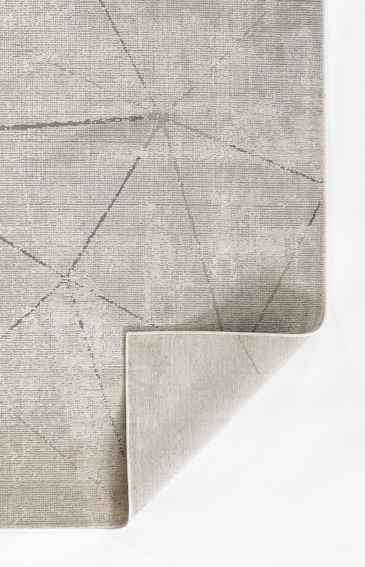 Gray geometric area rug with pale linear pattern; flat-weave look, folded corner reveals beige underside.