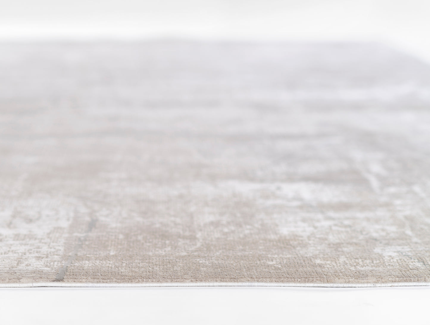 Neutral gray-beige rug with subtle distressed pattern, low-pile flat-weave texture, edge view.