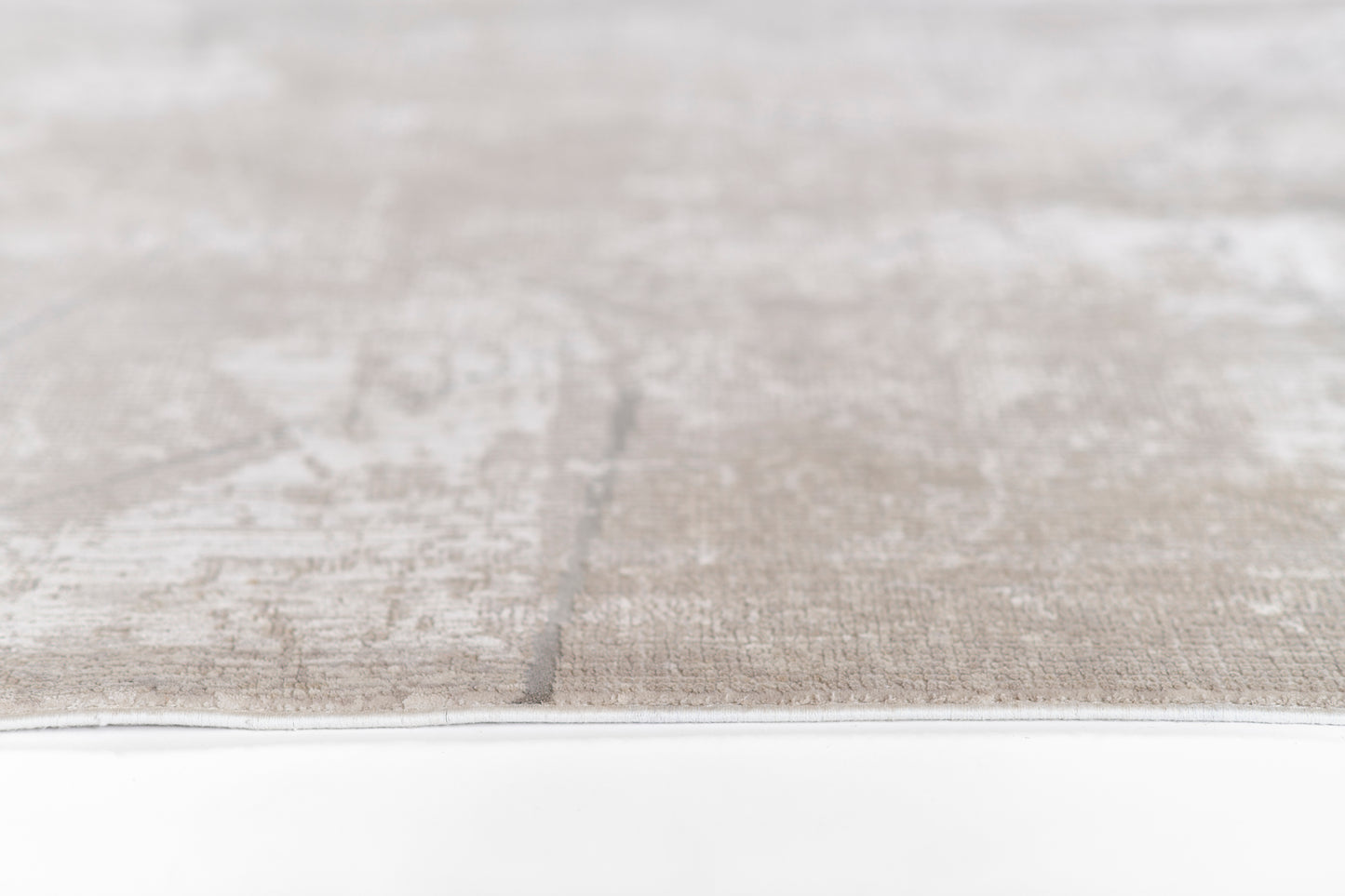 Close-up of a gray-beige woven rug with a subtle pattern and a light border.