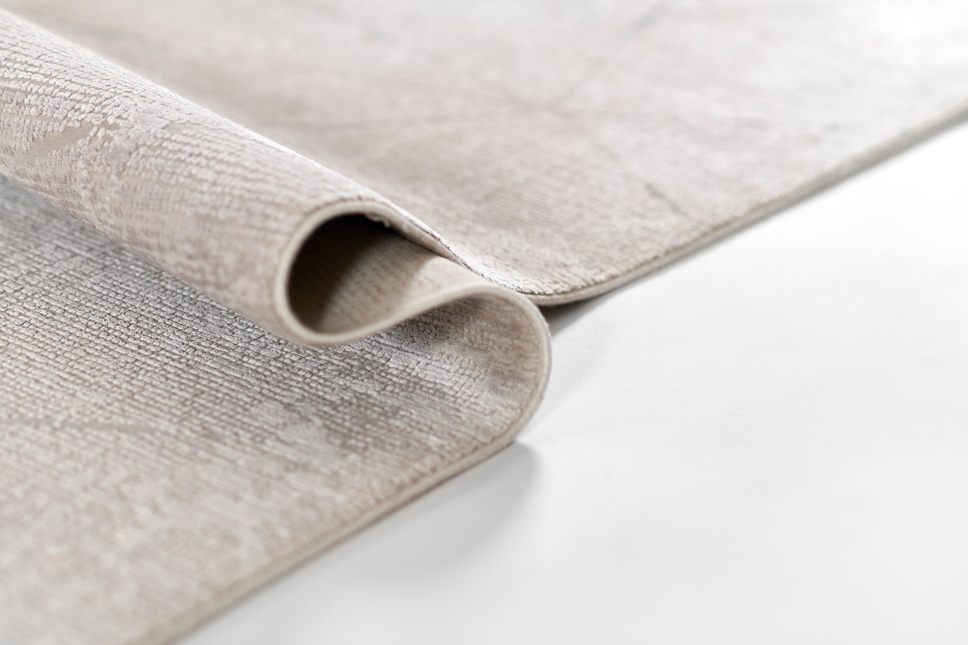 Light-gray textured woven rug, rolled edge, soft neutral fabric for modern living spaces.