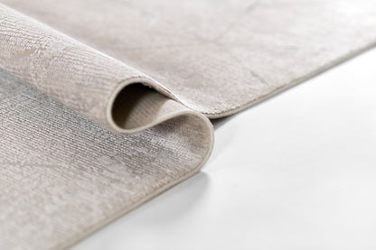 Light-gray textured woven rug, rolled edge, soft neutral fabric for modern living spaces.