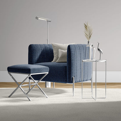 Navy blue textured armchair with matching ottoman and chrome legs, beside glass side table with vase and crane statue.