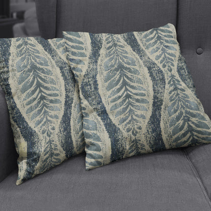 Two rectangular throw pillows in blue and cream with an indigo abstract botanical stripe pattern on a gray sofa.