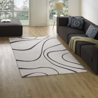 Ivory & charcoal abstract swirl area rug under a dark gray sectional sofa with blue patterned cushions.