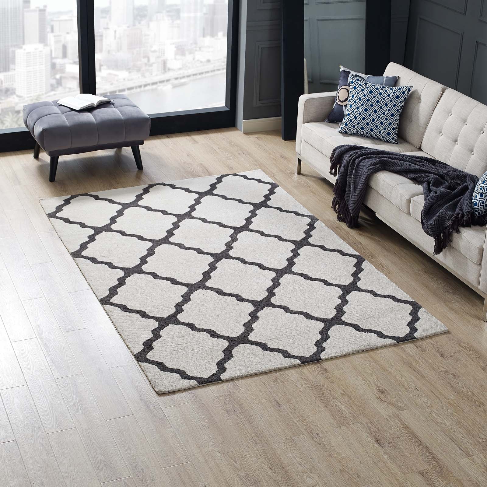 Beige area rug with dark gray lattice trellis on light wood floor; living room with tufted sofa and navy accents.