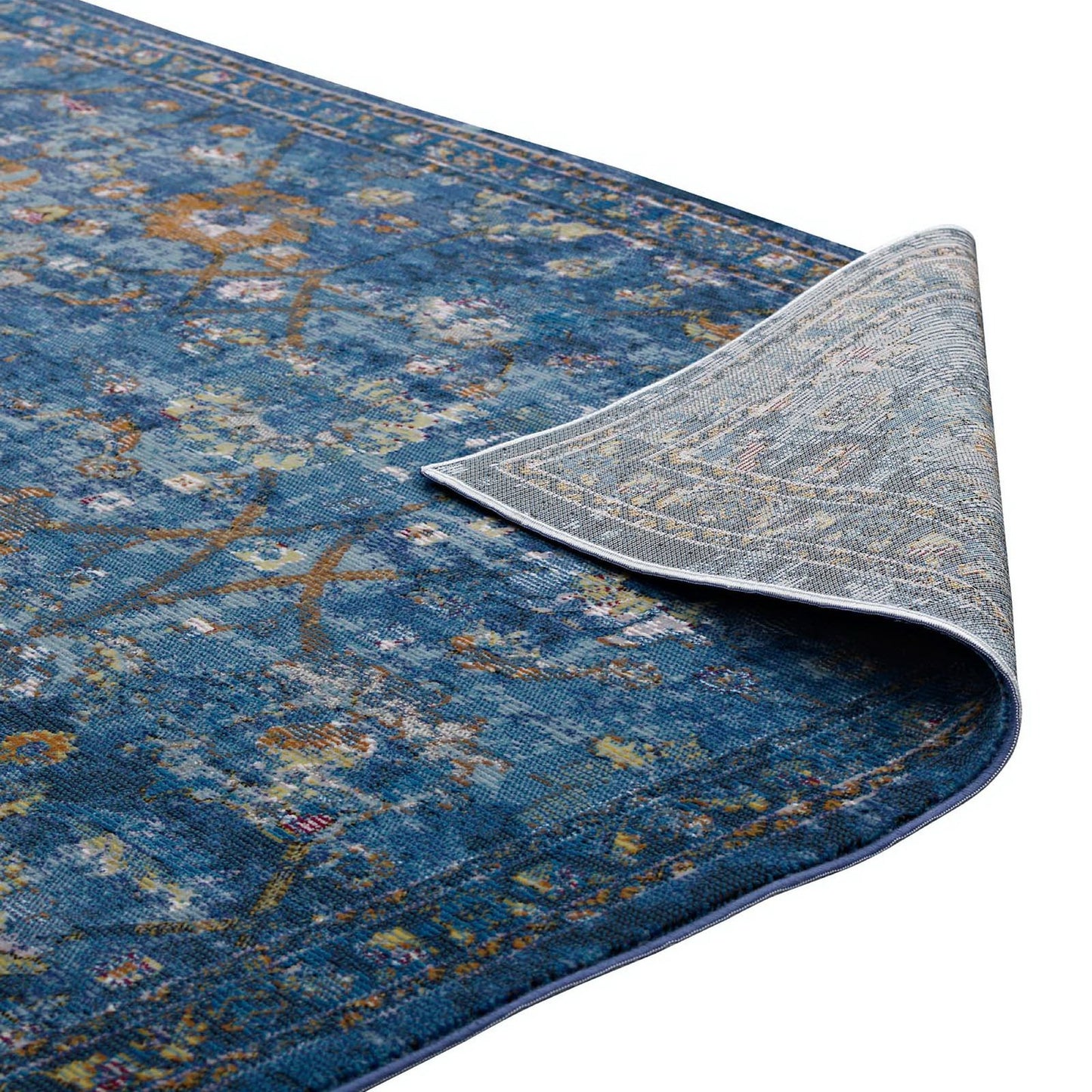 Blue distressed floral lattice area rug with multicolor accents; curled corner reveals light gray patterned back.