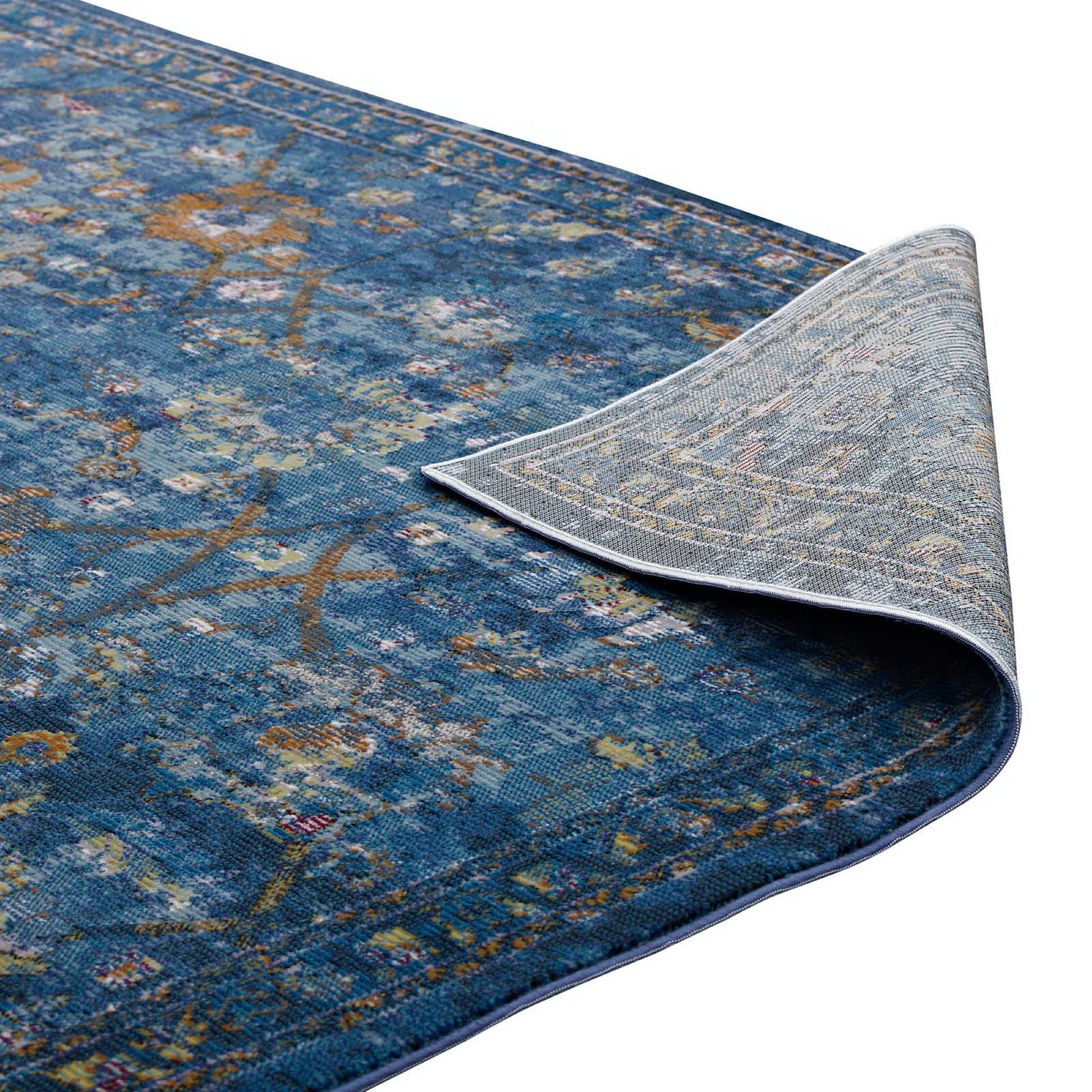 Blue distressed floral lattice area rug with multicolor accents; curled corner reveals light gray patterned back.