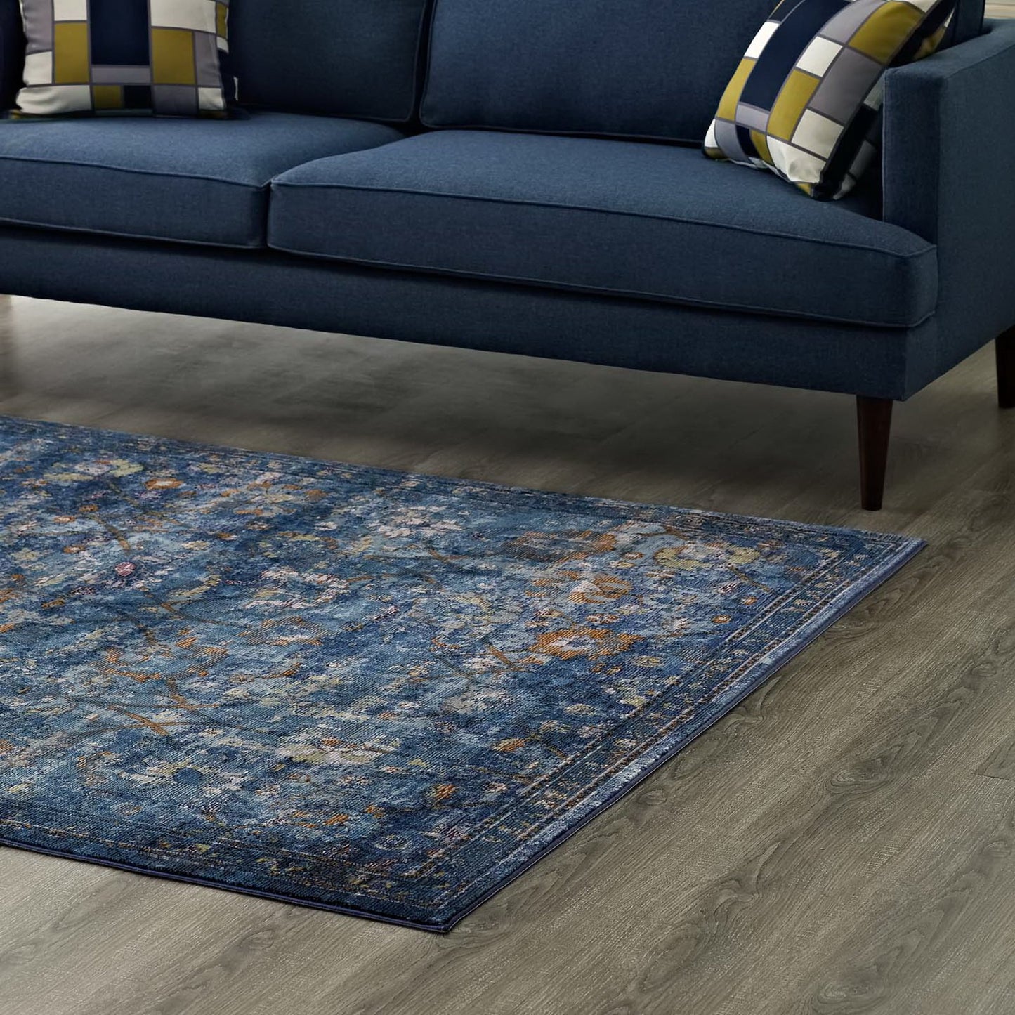 Dark blue distressed area rug with yellow and orange accents and a floral lattice pattern.