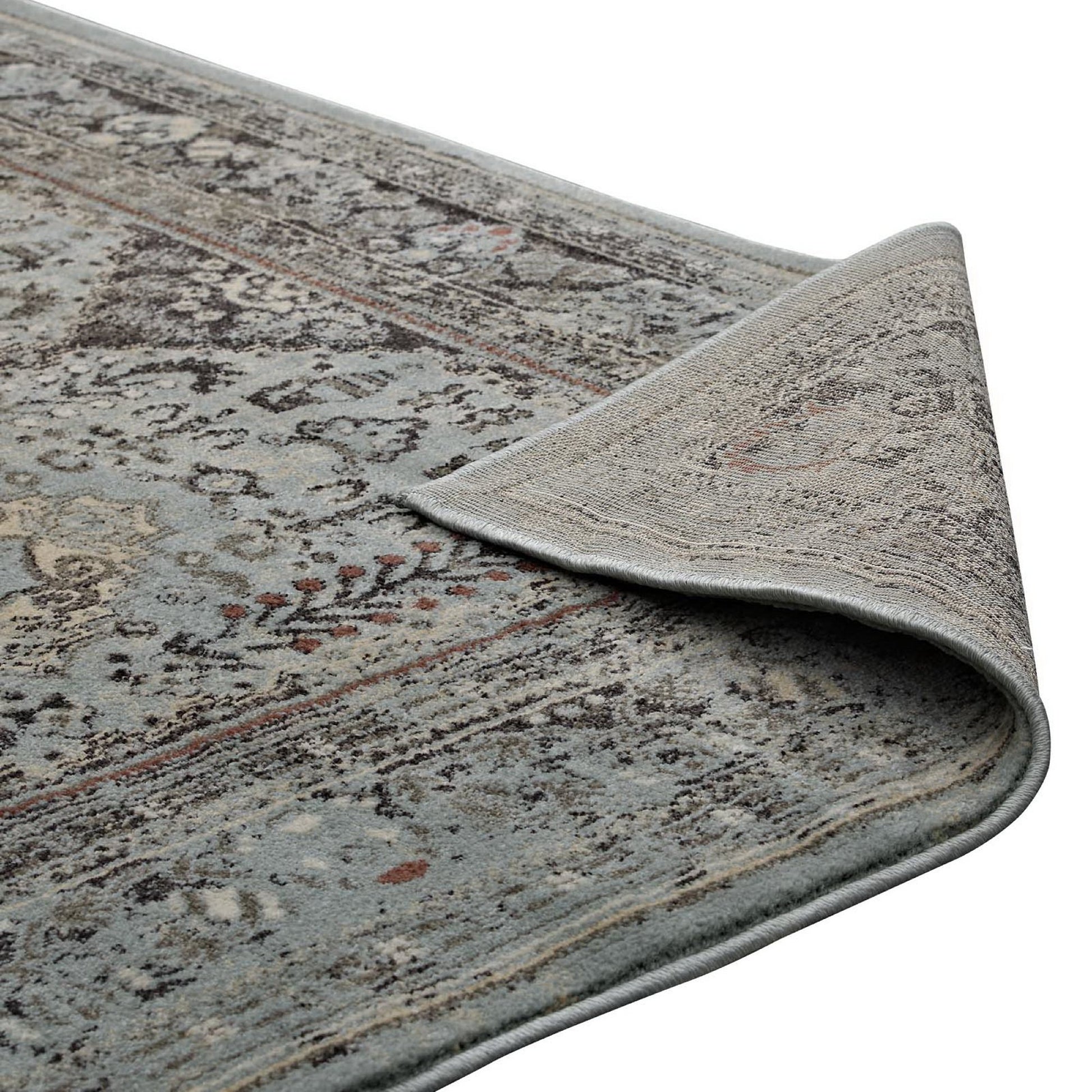 Brown and silver-blue distressed vintage floral lattice area rug with beige accents, curling corner showing soft pile and bound edge.