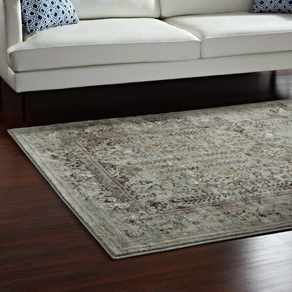 Distressed vintage floral lattice area rug in brown and silver-blue tones on a dark hardwood floor