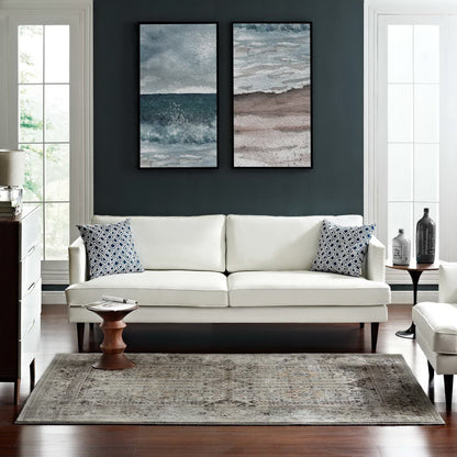 Cream leather sofa with navy pillows on a dark teal wall; two seascape prints, wooden side table, patterned beige rug.