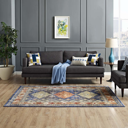 Multicolored distressed Southwestern diamond floral area rug in a paneled gray living room, with a dark gray fabric sofa, geometric cushions, and a blue throw.