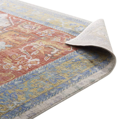 Vintage-style area rug with red central floral design and blue-gold borders; folded corner shows light backing.