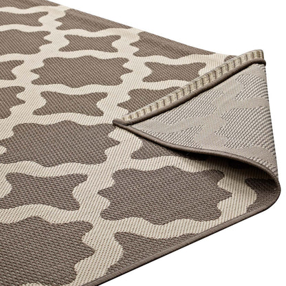 Woven rectangular rug in taupe and cream with a geometric quatrefoil pattern and textured surface; folded edge.