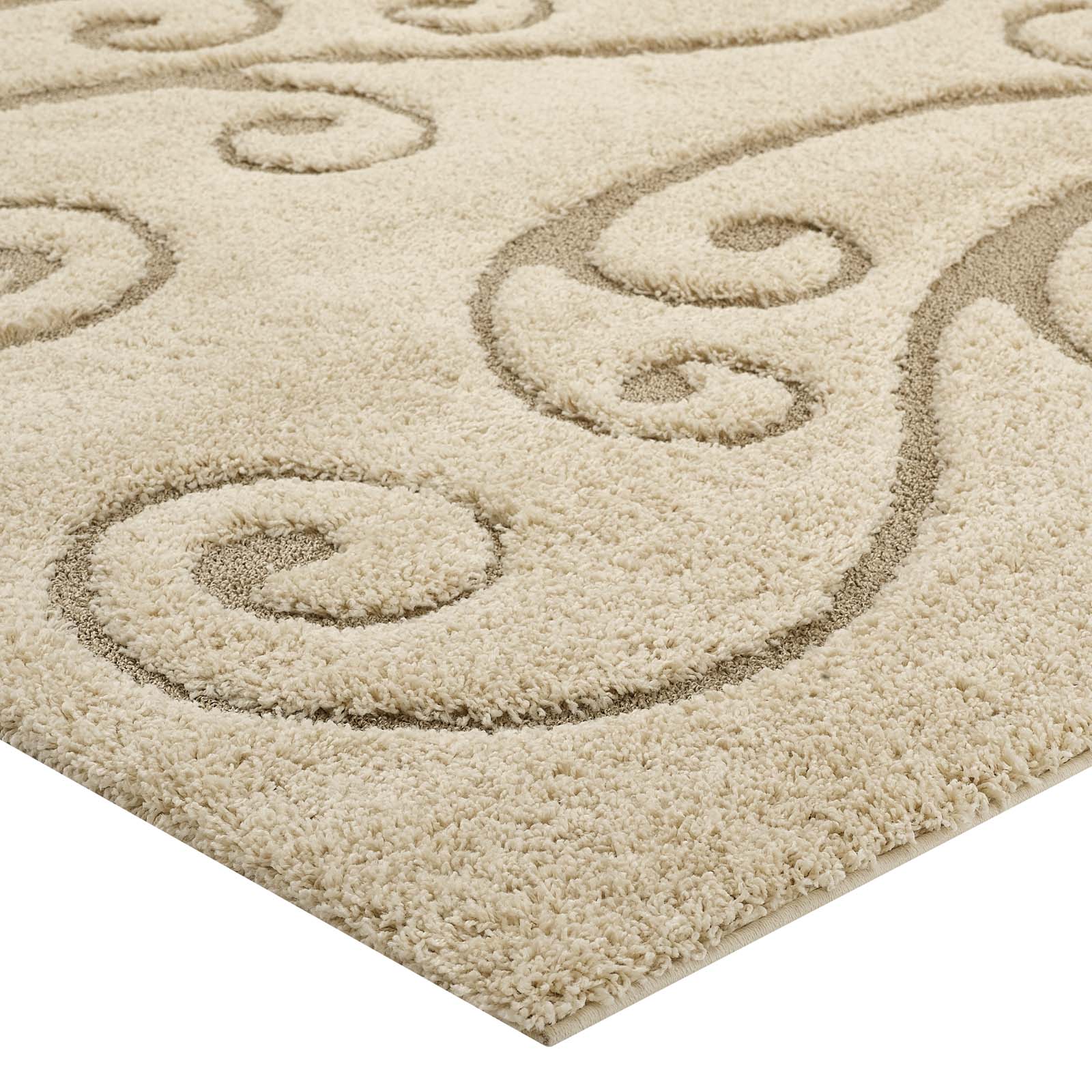 Beige plush area rug with dark decorative scroll-swirl pattern; thick soft pile and bound edge.