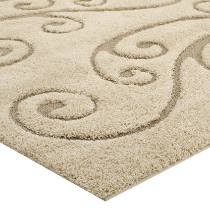 Beige plush area rug with dark decorative scroll-swirl pattern; thick soft pile and bound edge.