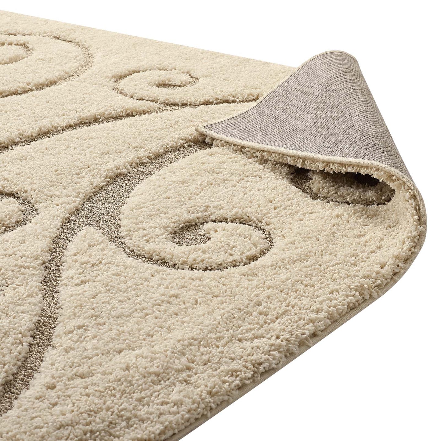 Cream beige shag rug with taupe scroll pattern; plush pile and rolled corner showing soft backing.