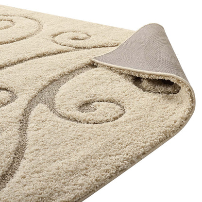 Cream beige shag rug with taupe scroll pattern; plush pile and rolled corner showing soft backing.