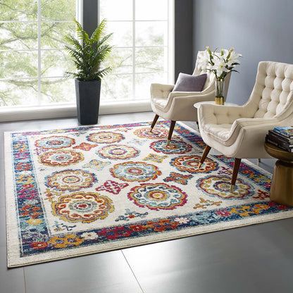 8x10 ornate area rug with a distressed floral Moroccan trellis pattern in ivory, blue, red, orange and yellow tones in a sunlit living room.