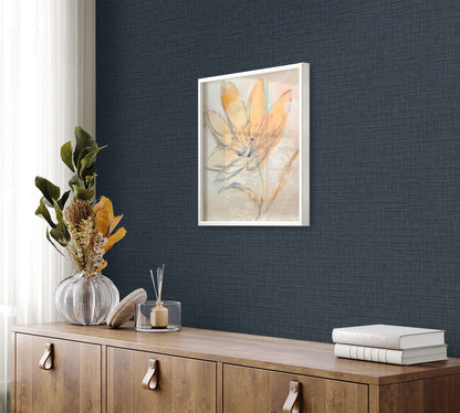 Framed botanical print with orange petals on pale background, white frame, navy wall above sideboard with vase and books.