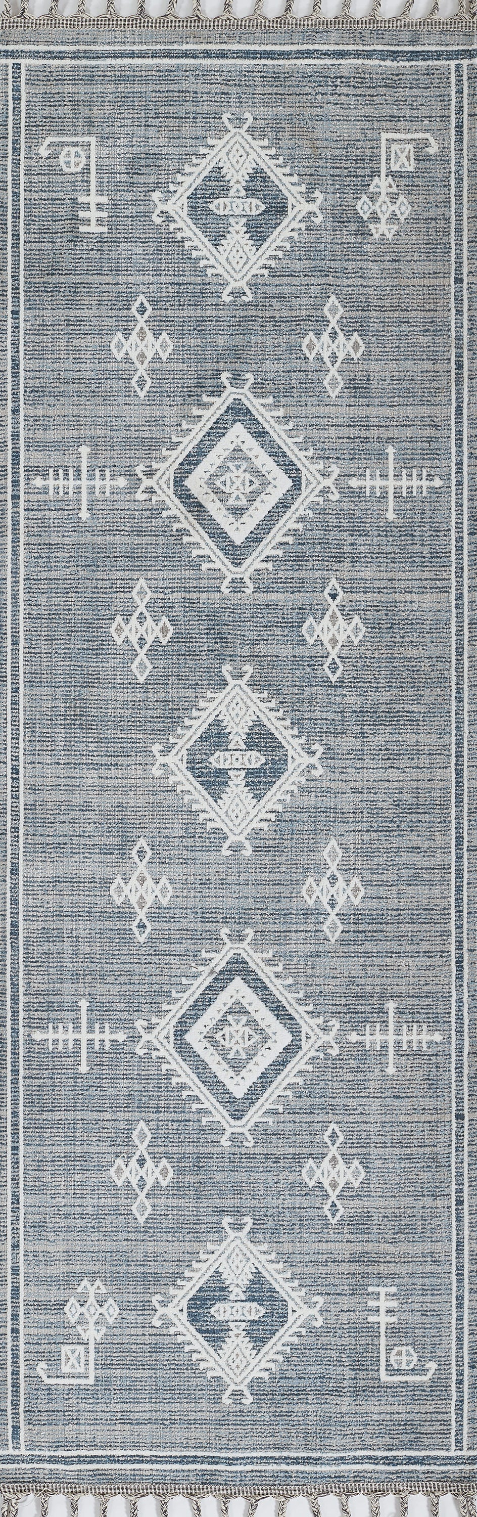 Blue woven rug with white geometric diamond motifs and fringe edge.