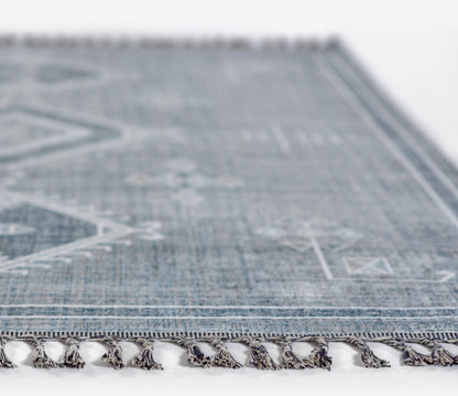 Blue geometric area rug with white patterns and tassel fringe along edge for living room decor.