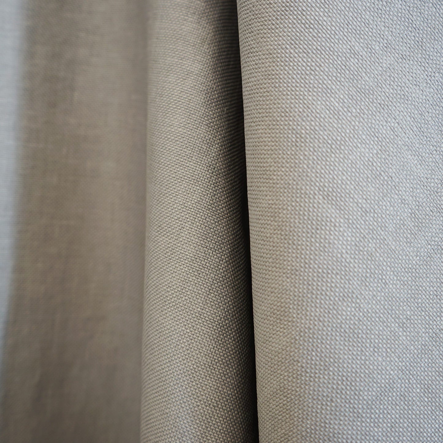 Beige and light gray woven fabric swatches with a textured linen-like weave and draped folds.