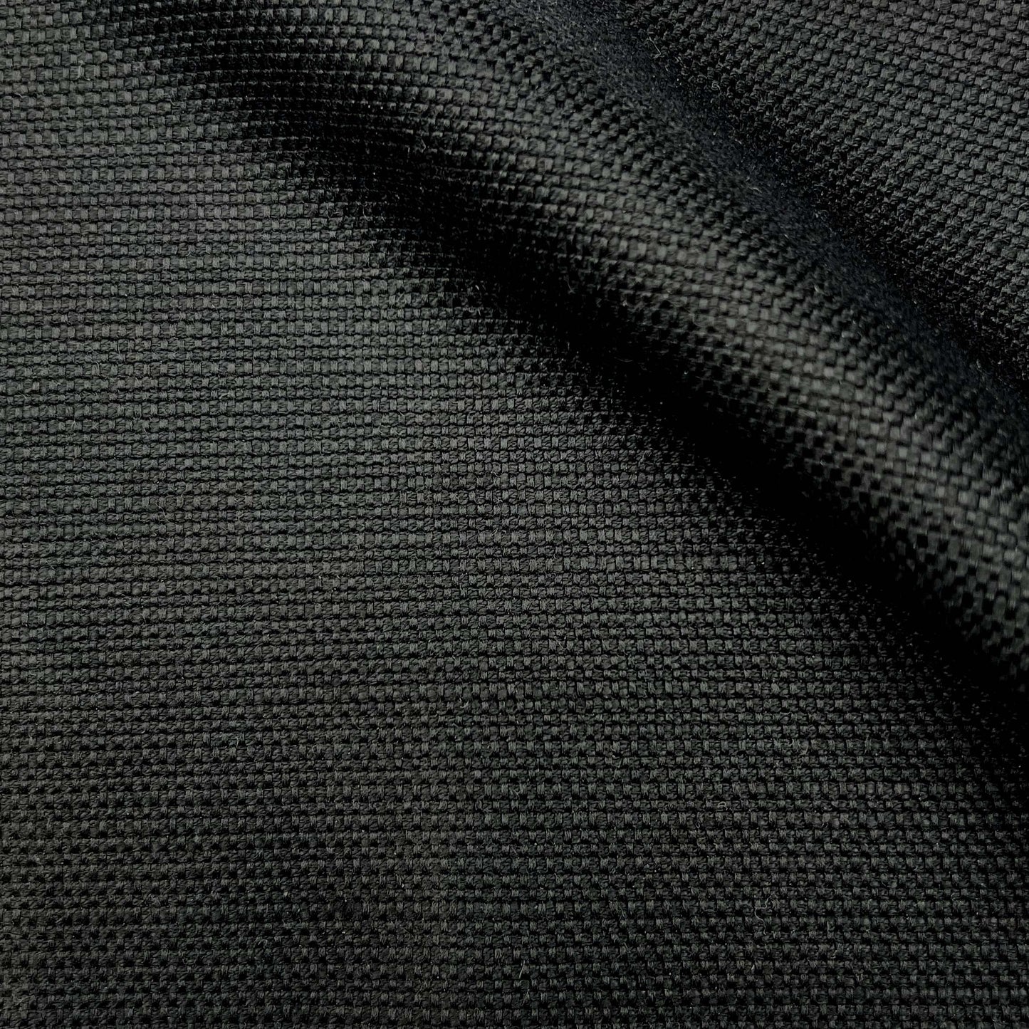 Close-up of black woven fabric with tight texture and a diagonal fold.