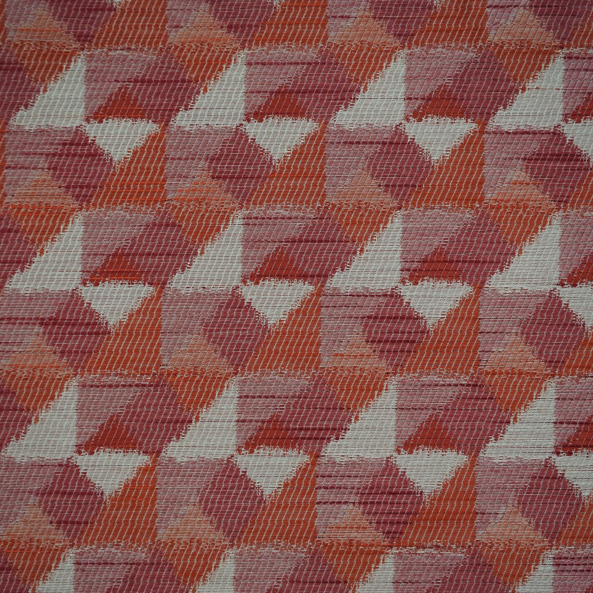 Woven fabric with a repeating geometric triangle pattern in burgundy, red, creme, beige, orange, rust and pink.