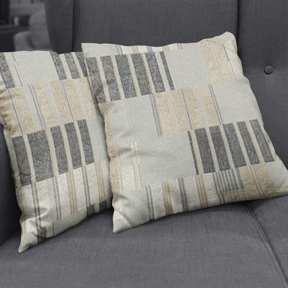 Two square throw pillows covered in beige, cream and gray striped geometric fabric on a dark gray sofa.