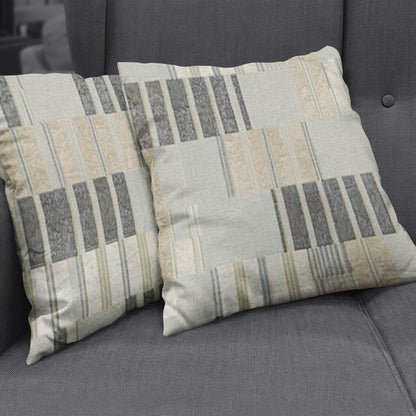 Two square throw pillows covered in beige, cream and gray striped geometric fabric on a dark gray sofa.