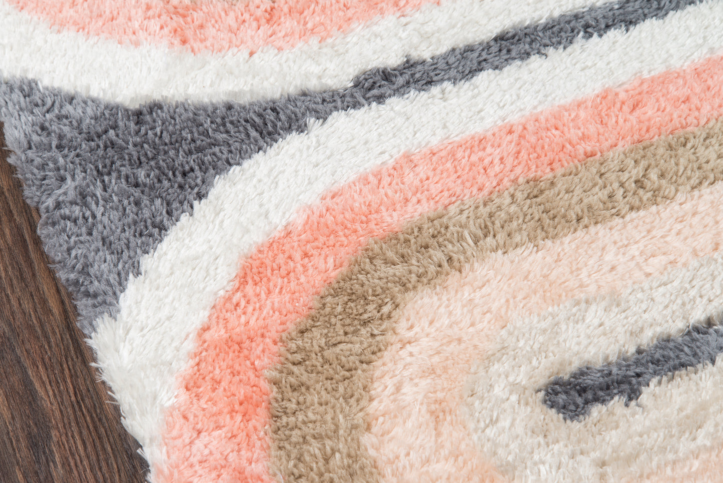 Shaggy retro-area rug with concentric pastel stripes in gray, white, pink, beige; soft textured pile on wood floor.