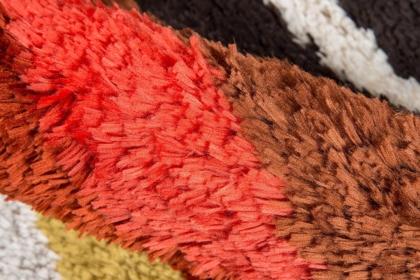 Close-up of a retro shag rug with red and brown plush fibers, thick pile, multicolor stripes for cozy floor decor.