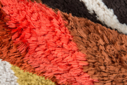 Close-up of a retro shag rug with red and brown plush fibers, thick pile, multicolor stripes for cozy floor decor.
