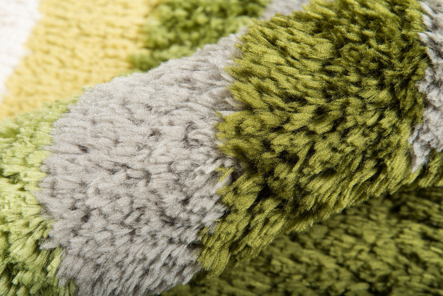 Close-up of a retro shag rug with thick loop pile in olive green, gray and yellow.