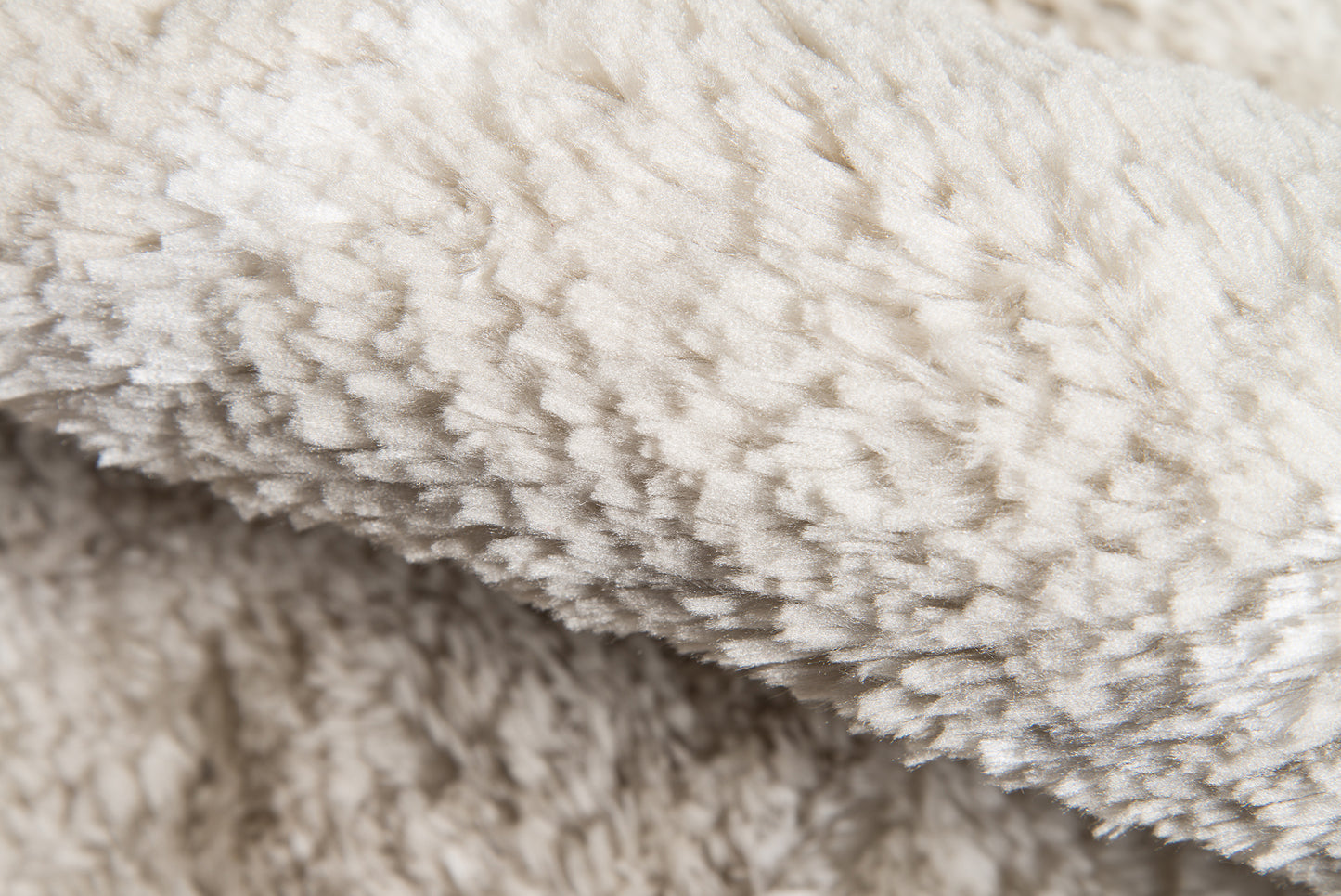 Cream-taupe shaggy rug with rolled edge and dense pile, 2' x 3'.