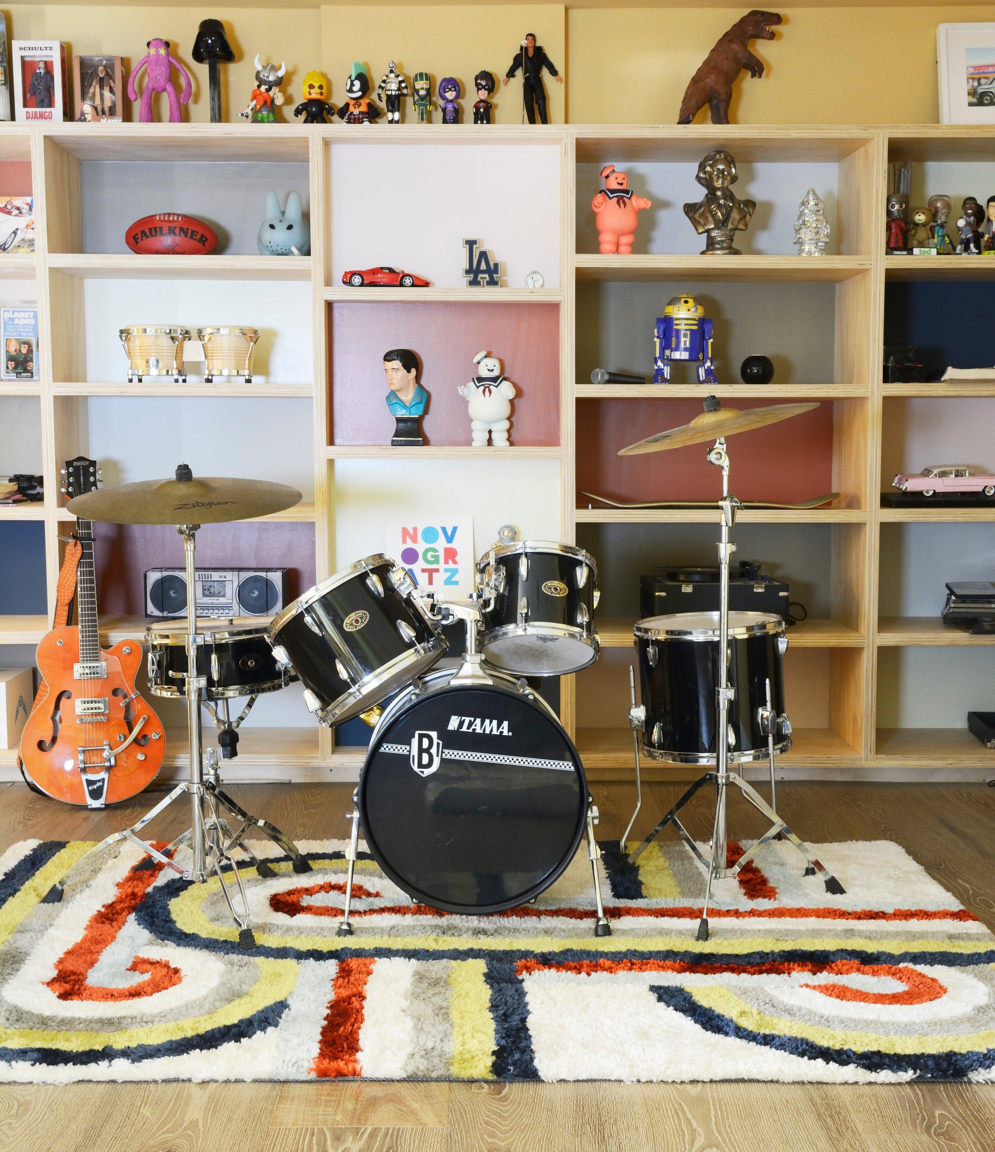 Colorful geometric rug on a floor with a backdrop of wooden shelves filled with toys.