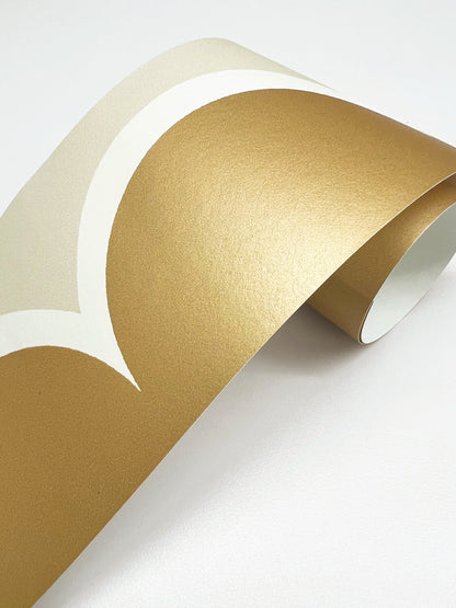 Gold metallic foil wallpaper trim with a linen scallop pattern; rolled trim showing a reflective finish.