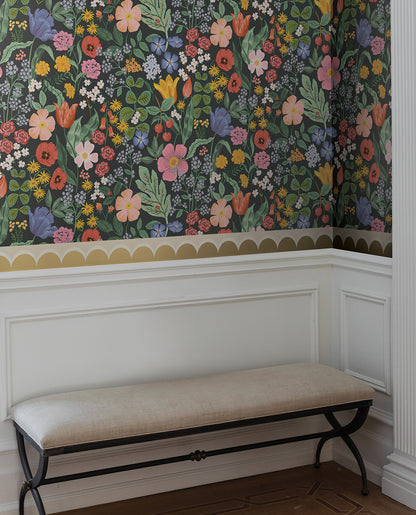 Yellow geometric linen scallop wallpaper trim on wall with white wainscoting and beige cushioned bench.