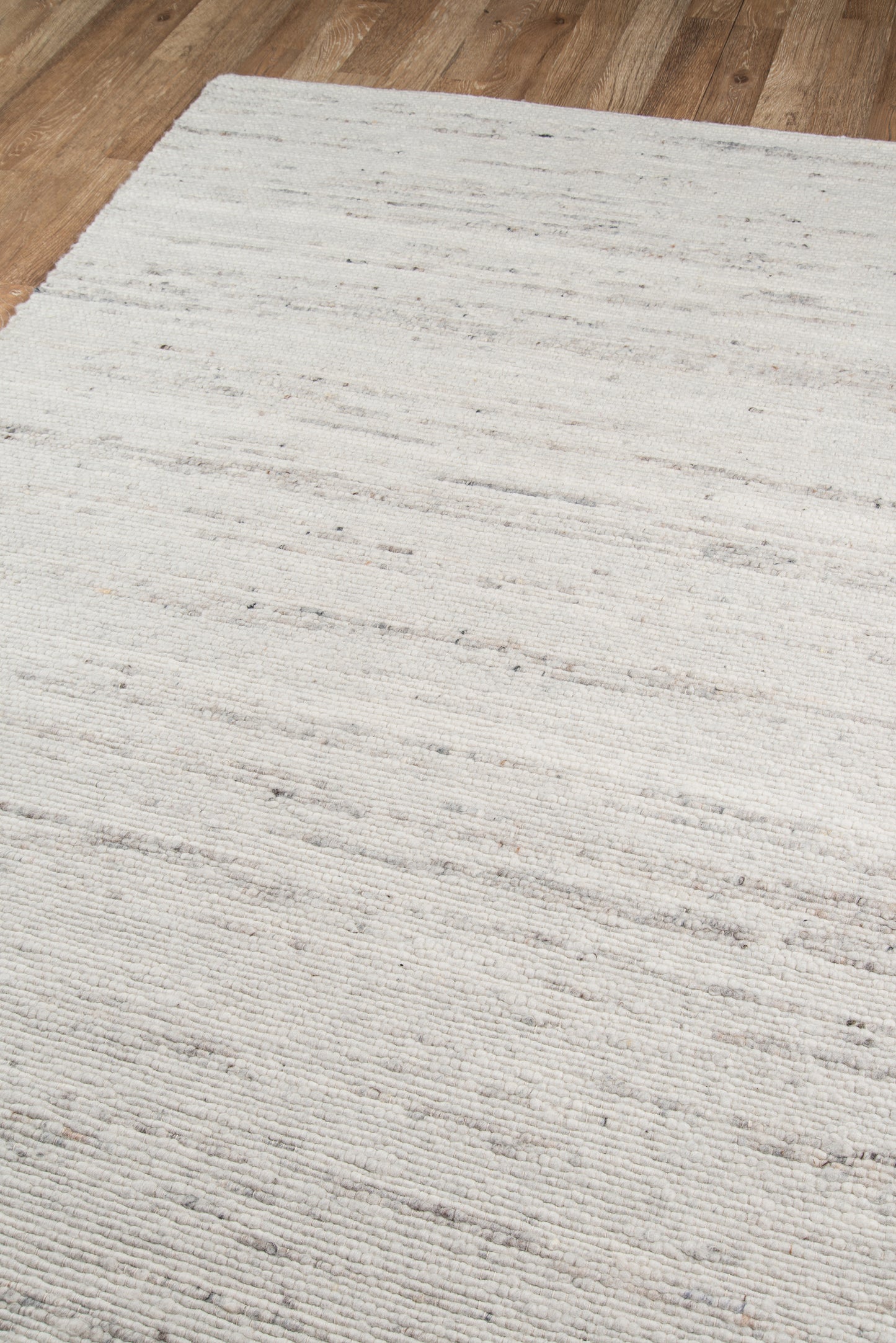Ivory rug with subtle gray marbling texture on light wood floor; rectangular, contemporary woven style.