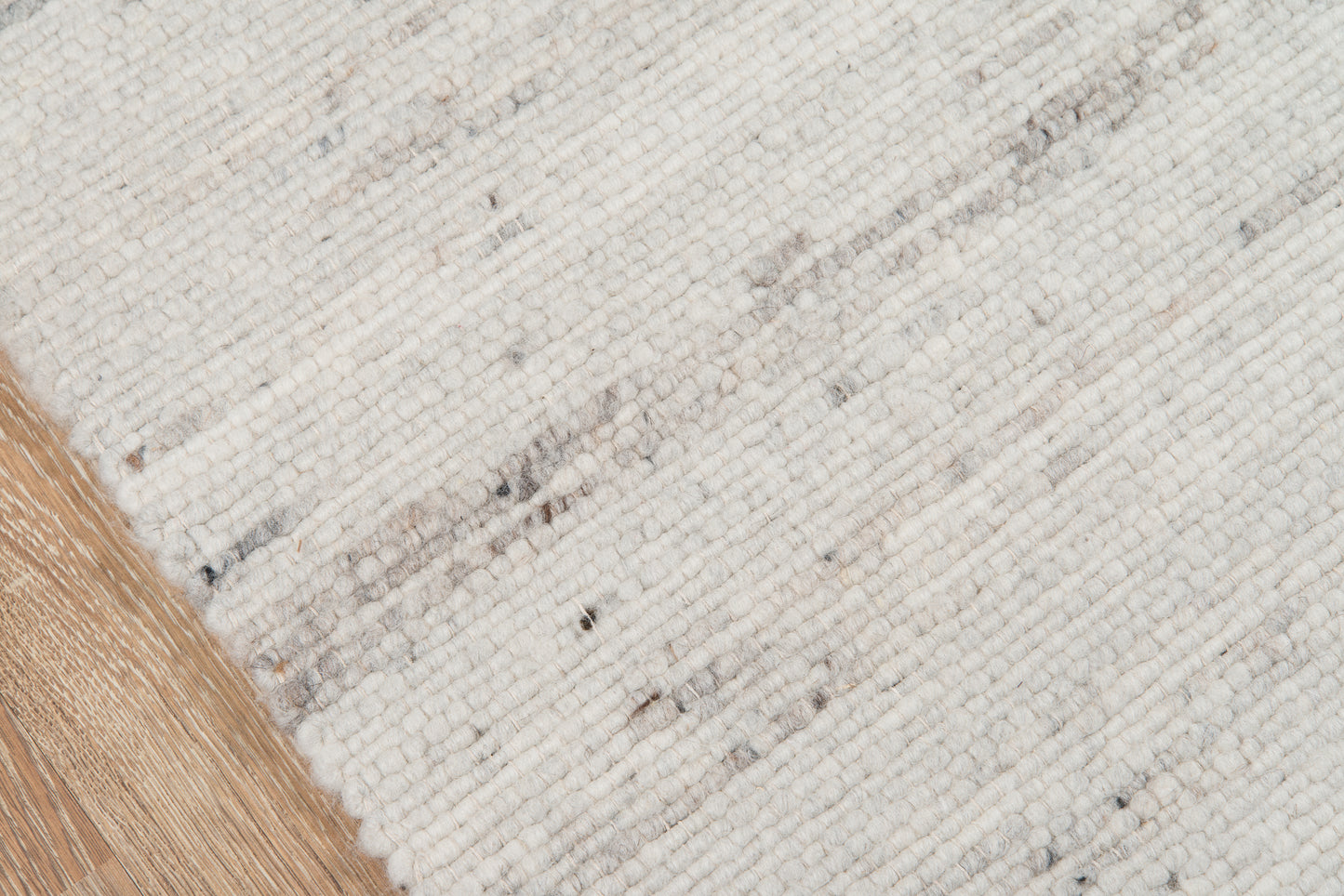 Cream ivory woven rug with subtle gray flecks and a light tan fringe along the edge.