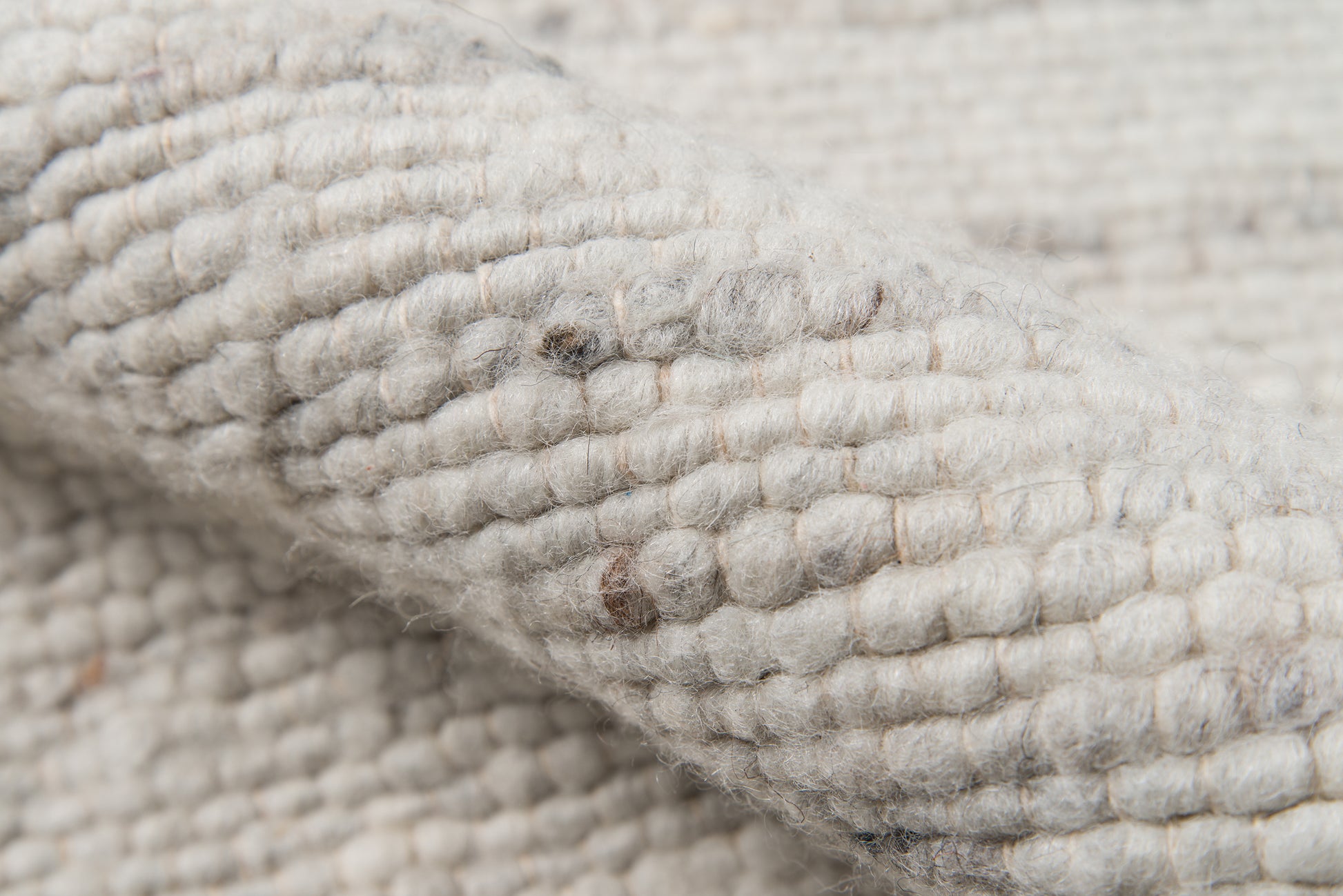 Close-up of ivory cream chunky knit wool fabric with thick looped texture and soft, cozy look.