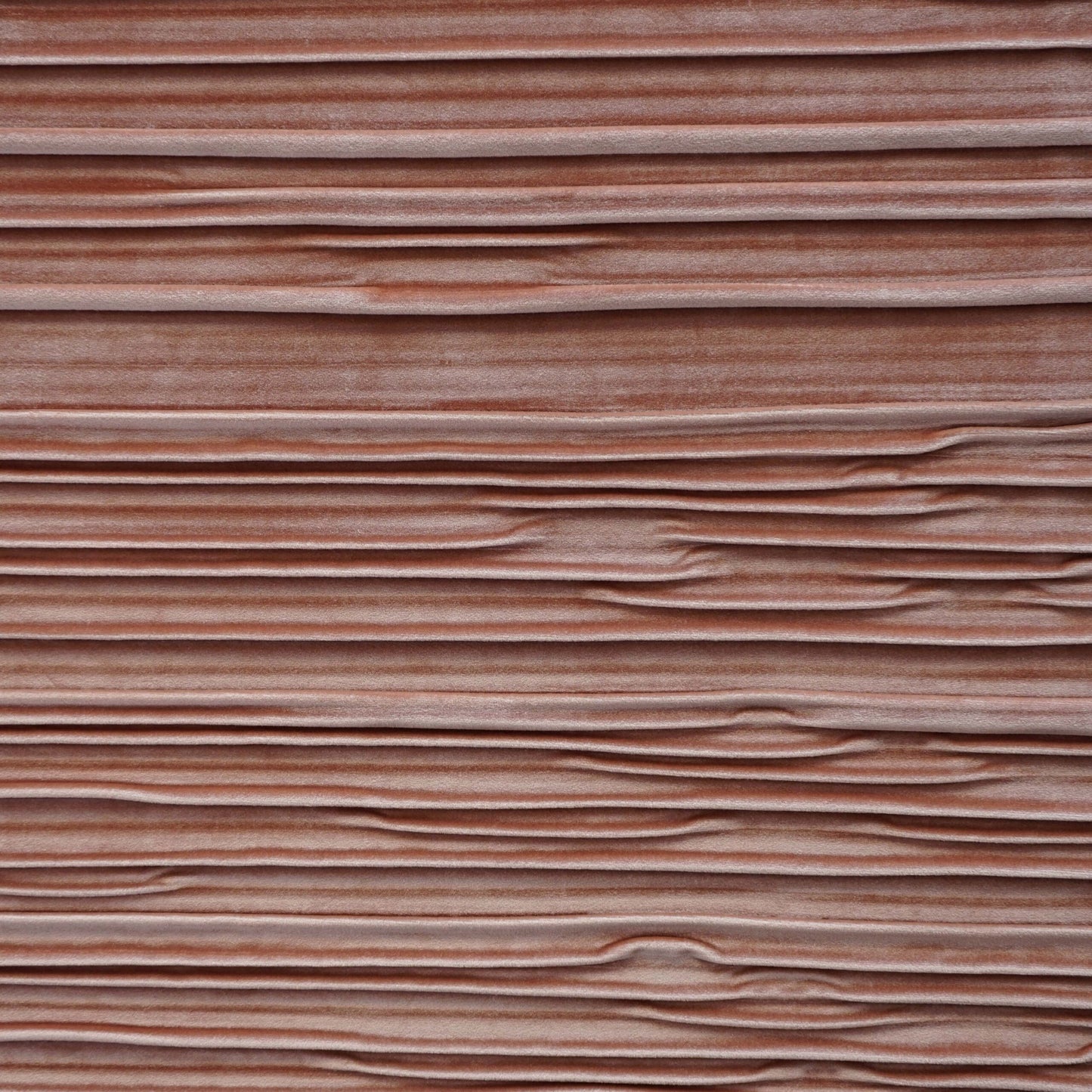 Close-up of pink, peach, and coral velvet fabric with a pleated texture.