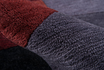 Close-up of plush boucle fabric in red and blue-gray color blocks, soft textured weave and folded edge.