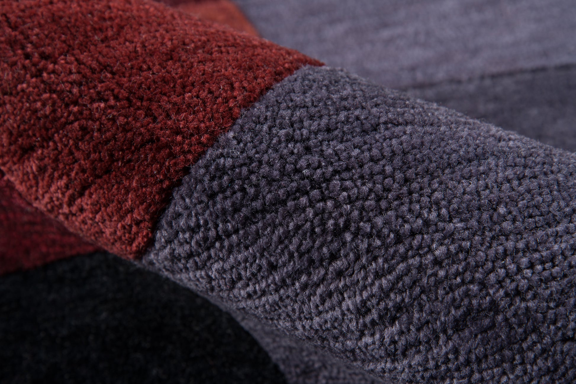 Close-up of plush burgundy & slate blue boucle fabric; soft textured throw blanket with color-block design.