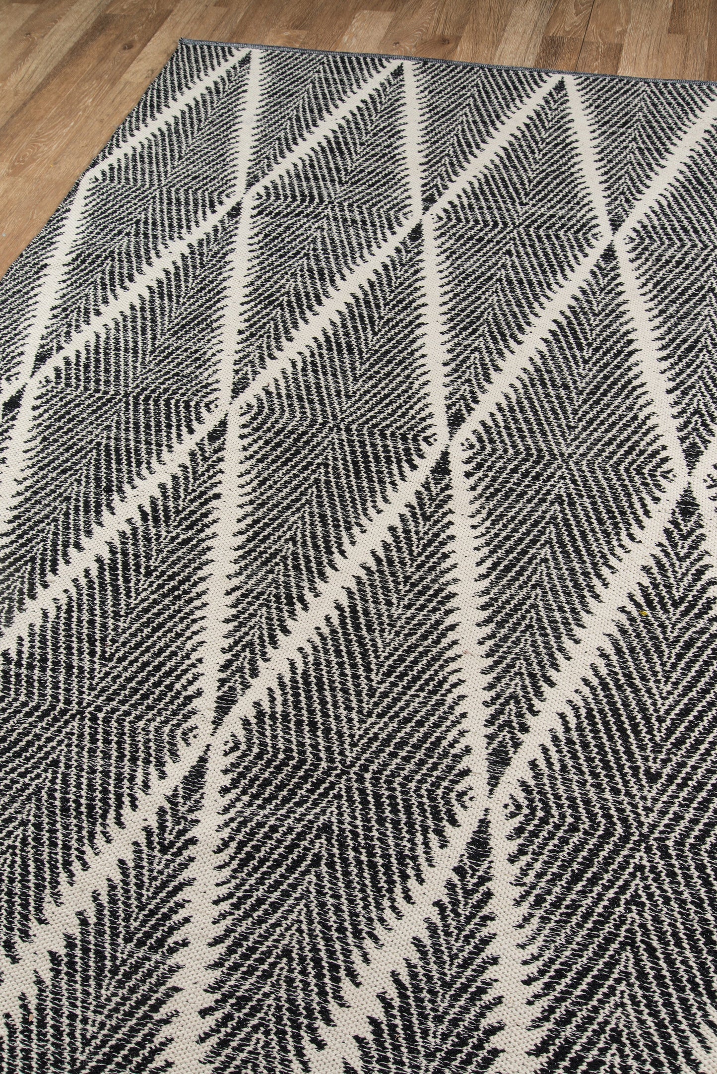 Black and white geometric rug featuring chevron and diamond starburst pattern on a wooden floor.
