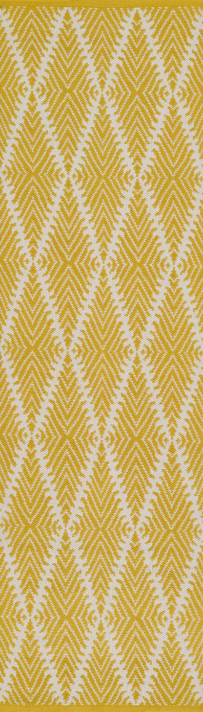 Mustard yellow woven fabric with white chevron/diamond geometric pattern, vibrant decorative textile.